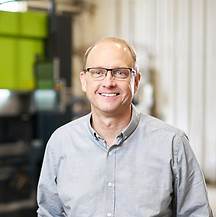 A man in glasses overseeing metal fabrication machinery.
