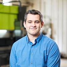 A man in a blue shirt working at a custom metal fabrication factory.
